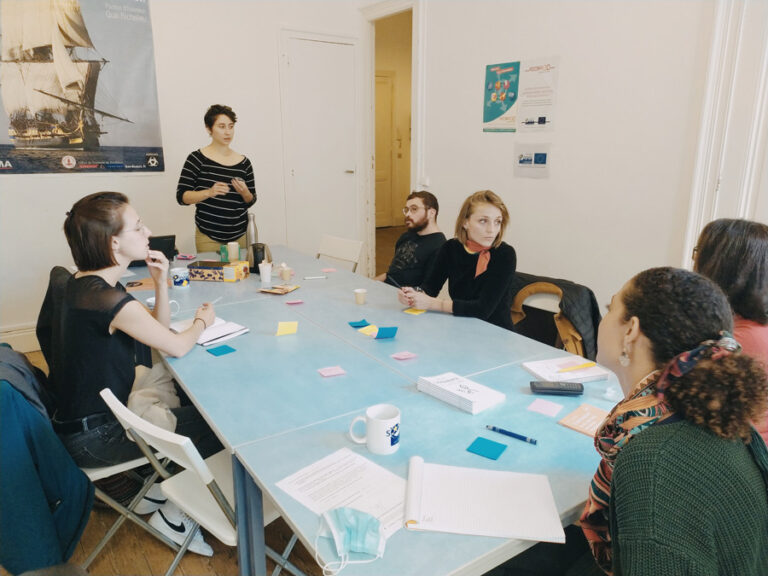 Des personnes autour d'une table. Des posts its et feuilles sur la table